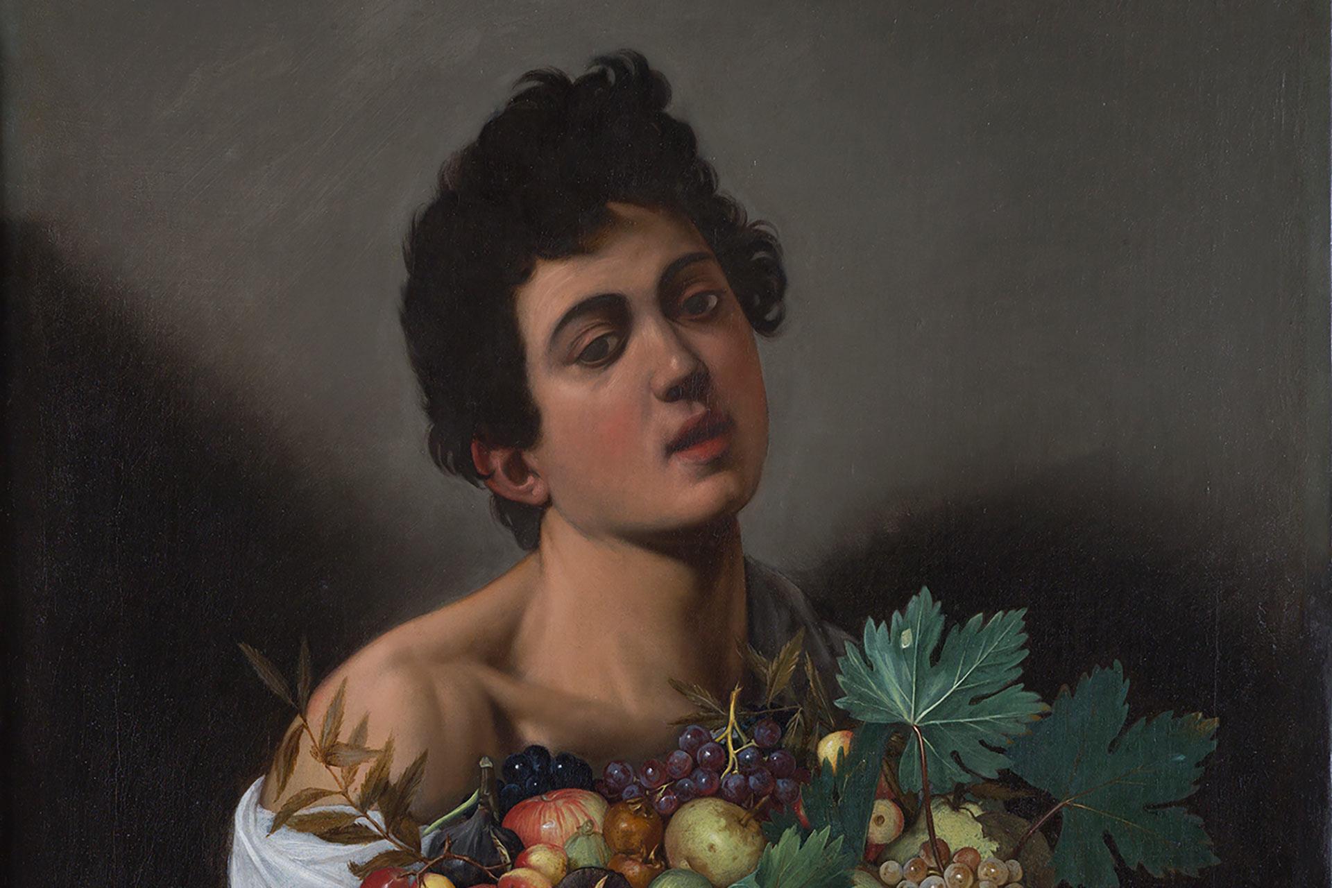 A classical painting of a young man with dark, curly hair gazing forward, draped in a white cloth, holding a large basket filled with various fruits and leaves against a dark background.